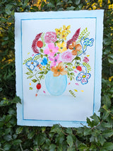 Original watercolor painting depicting a translucent blue glass vase holding a myriad of colorful flower bouquet.