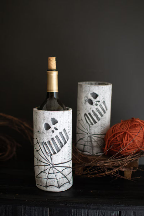 Wine bottle in a decorative clay holder with spider web design on a dark background