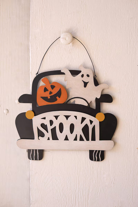 door hangar of smiling ghost and pumpkin driving black car with spooky grill