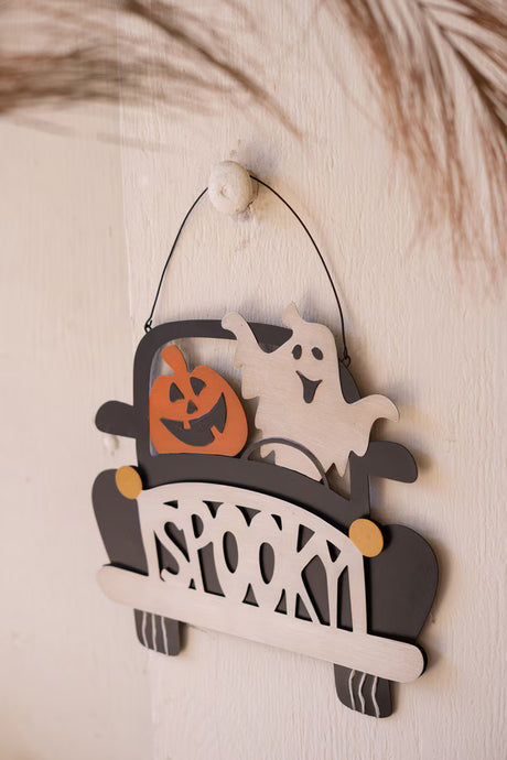 smiling ghost and pumpkin driving black car with spooky grill - door hangar - angled view