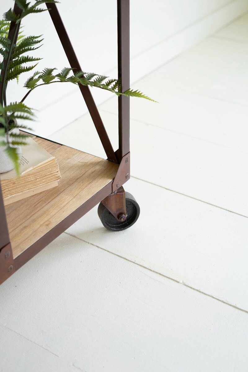 Wooden shelf with metal legs on a white floor showing caster wheel