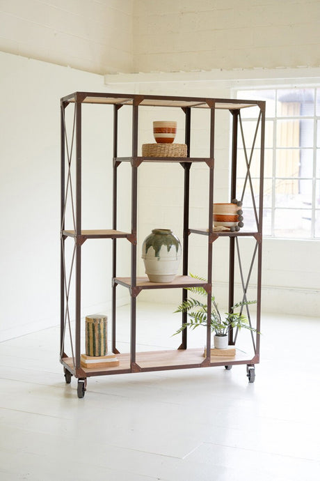 Industrial-style metal and wood bookshelf with decorative items in a bright room.