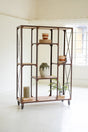 Industrial-style metal and wood bookshelf with decorative items in a bright room.