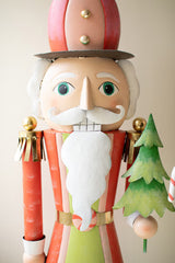 Nutcracker figurine with a Christmas tree and candy cane on a plain background