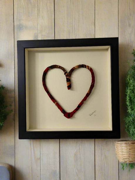 dark red color mix fabric heart in black frame behind museum glass hung on wood slab wall