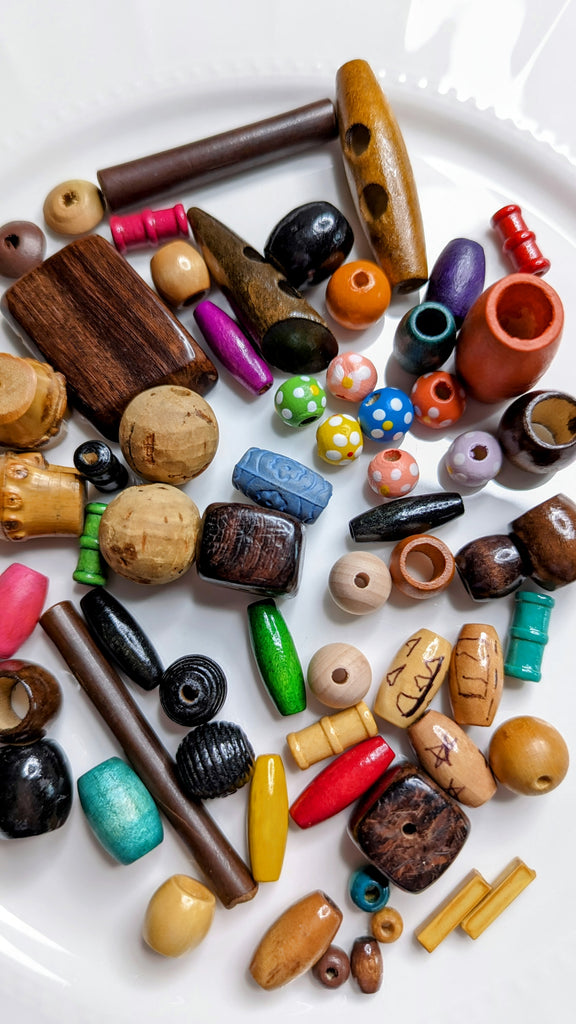collection of colorful wood beads oval, rectangle, round, wooden sticks - close up of fewer beads but showing all varieties and colors and shapes