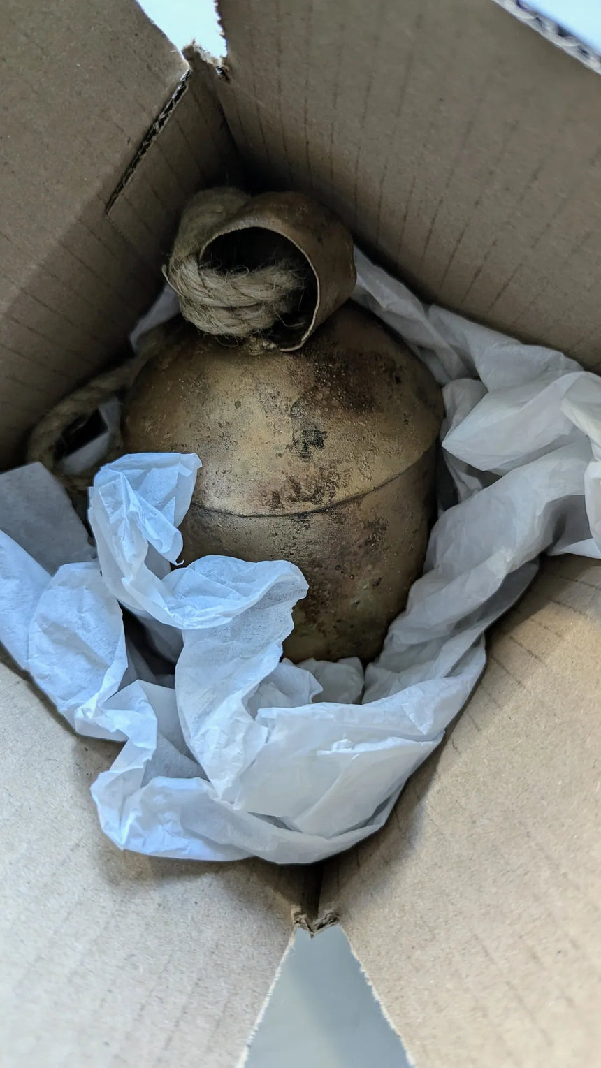 Photo of carefully wrapped and packaged bell in cardboard box with tissue paper