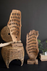 Wooden sculptures with wicker chair against a dark background