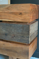 Thick wooden shelves with a dark gray and light brown finish against a dark blue wall - close-up of corner wood detail