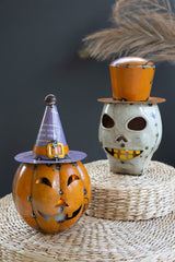 Two Halloween-themed decorative items one orange pumpkin with purple witch hat and a skull with orange top hat