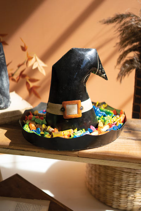 Decorative witch hat with colorful candy base on a wooden surface