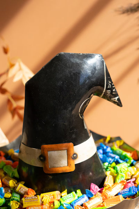 Black witch hat with colorful candies on a brown background