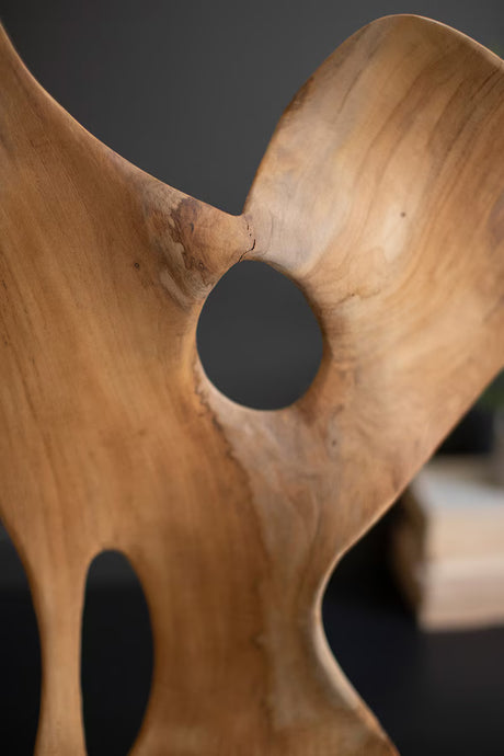 Wooden sculpture with a central circular hole on a dark background