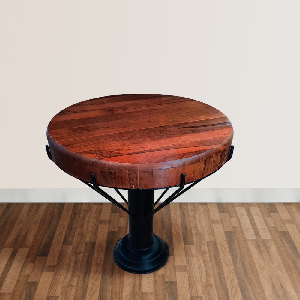 accent table with round mango wood table top and black iron pedestal base on wood floor with white wall background