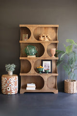 Wooden shelving unit with horizontal pill-shaped shelving sections holding decorative items against a dark wall
