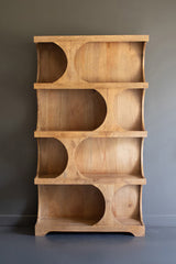 Wooden shelving unit with horizontal pill-shaped shelving sections - empty standing against a gray wall