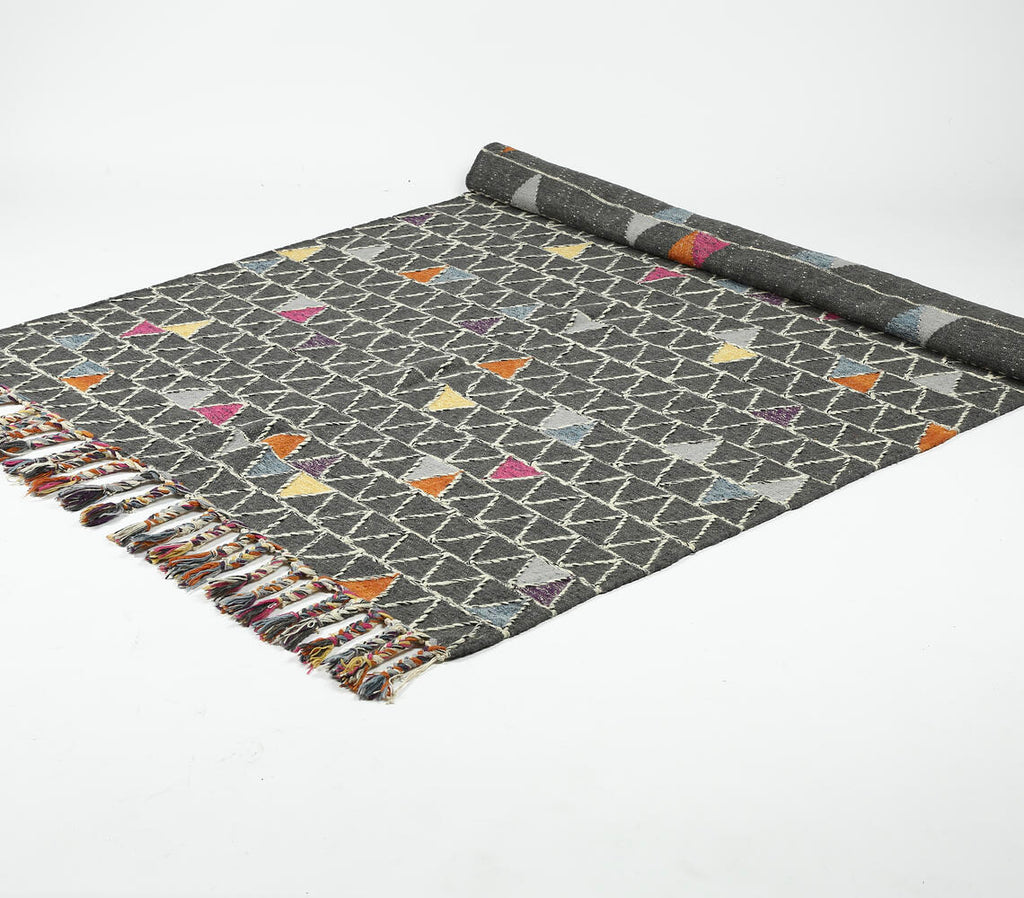 handwoven wool rug with color pop triangle design - partially rolled up