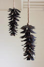 dark brown metal pine cone ornaments hanging from twine