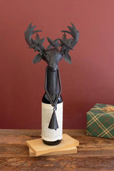 dark metal deer wine bottle topper with bell in its hands atop a small bottle