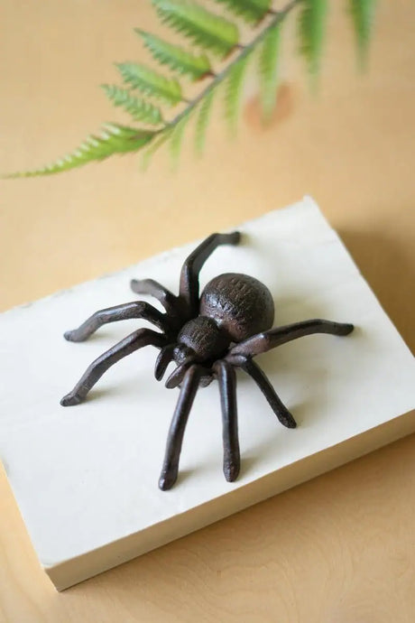 black cast iron spider sitting on off white block of marble - halloween decor