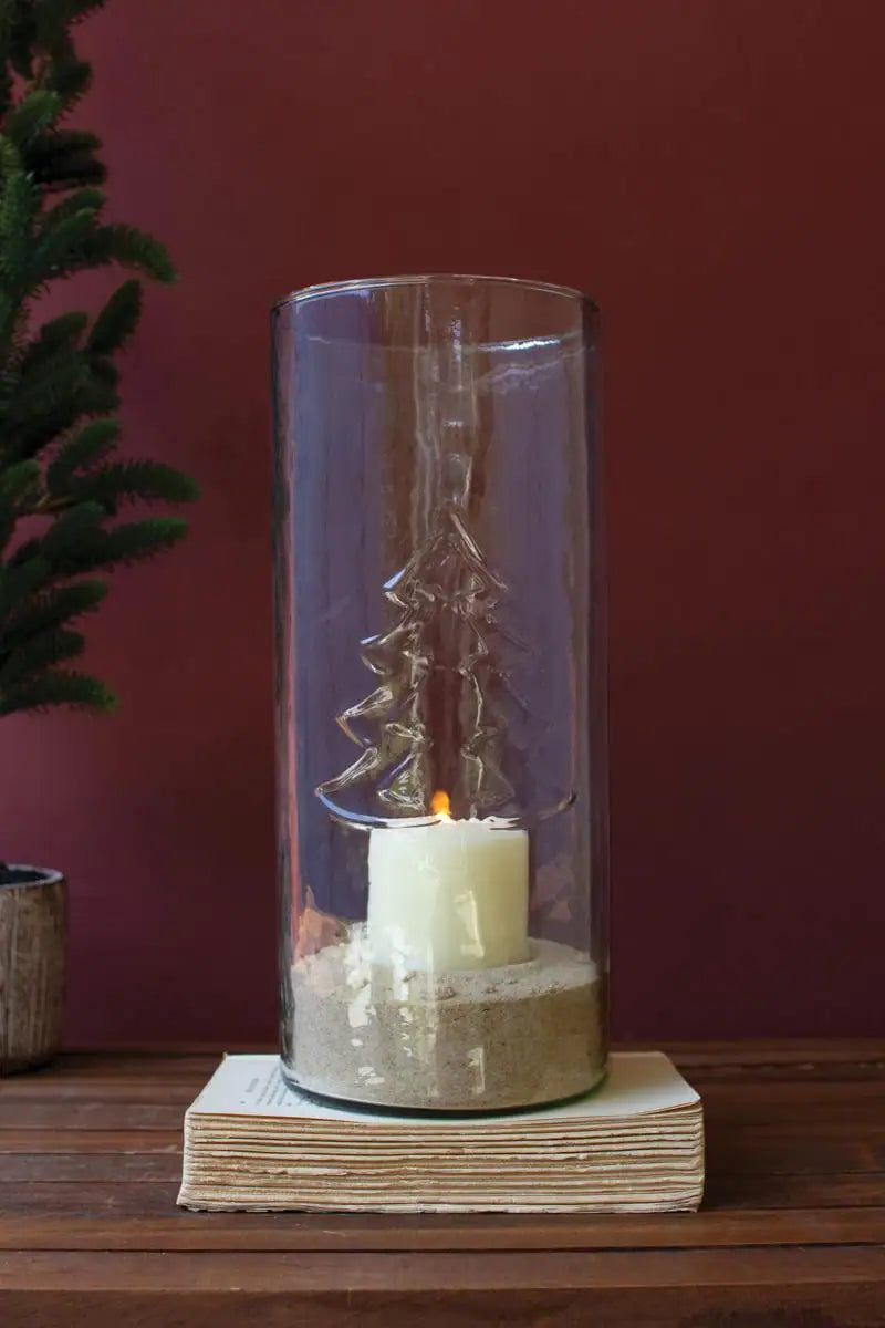 tall glass christmas cylinder filled with some sand with short lit candle on top