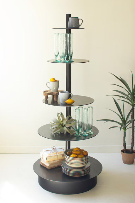 Round, black 5-tiered shelf with decorative items against a white wall