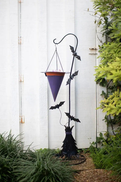 witch's hat candy holder suspended from curved hook end of black broom and bats - halloween decor