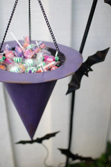 close up of upside down witch's hat candy holder with bats in background