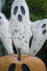 orange smiling jack-o-lantern with 3 white ghosts emerging from the top - close up of middle ghost