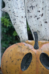 orange smiling jack-o-lantern with 3 white ghosts emerging from the top - close up of the top of the pumpkin