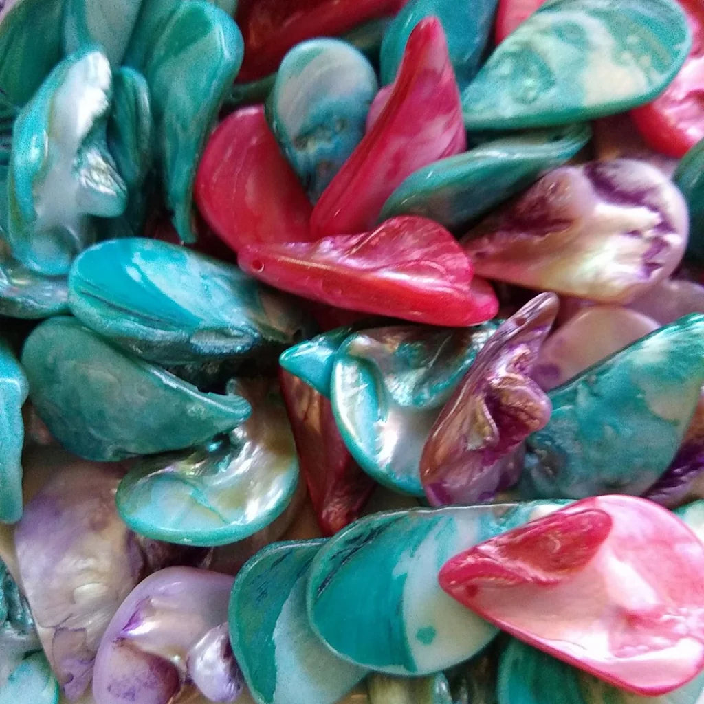 collection of tear drop shaped, mother-of-pearl beads, dyed in fuchsia, lilac and blue - close-up