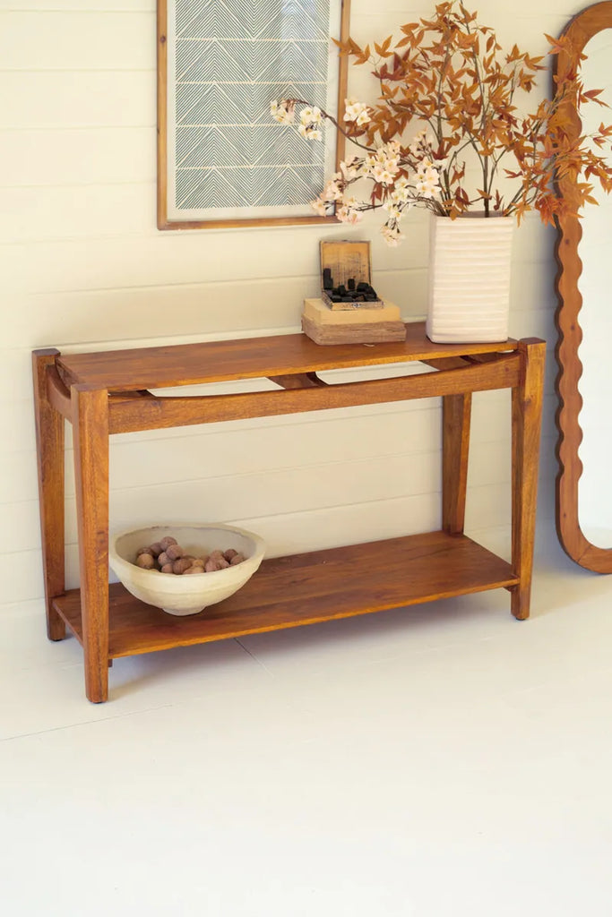 warm colored mango wood console table shown against a wall with other decorative items