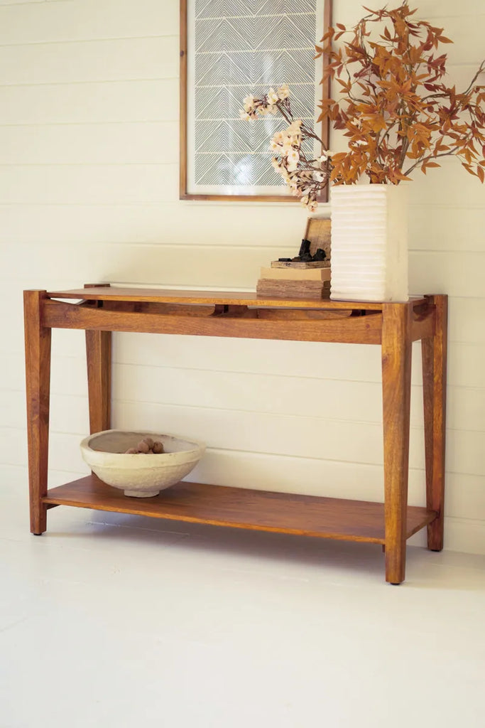 warm colored mango wood console table shown against a wall seen alternatively diagonally from the right