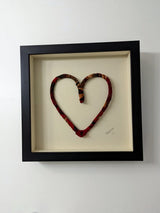 multicolored recycled fabric heart in black wood frame behind museum glass