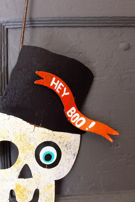 close-up of skelton's face with one eye and tophat with banner 'hey boo'