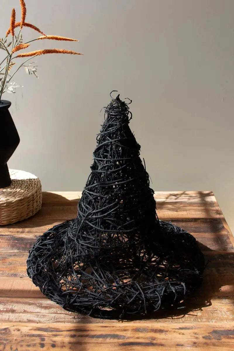 black twig witch's hat shown sitting on wood table - slightly angled down perspective