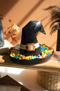 black witch's hat candy holder with simulated white belt and orange buckle holding candy it its rim