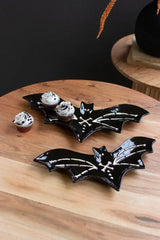 2 black ceramic bat platters with white bones detail - shown holding cupcakes