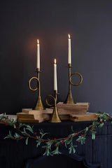 showing all 3 taper candle holders with long white lit candles sitting on a black mantel