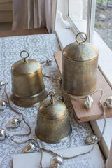 3 brass finish bells - sitting on window sill and tablecloth covered table