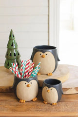 3 ceramic penguin planters of different sizes, one holding colorful straws