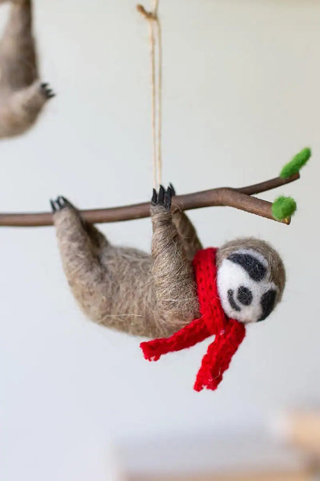 close up of sloth with red scarf hanging from a brach