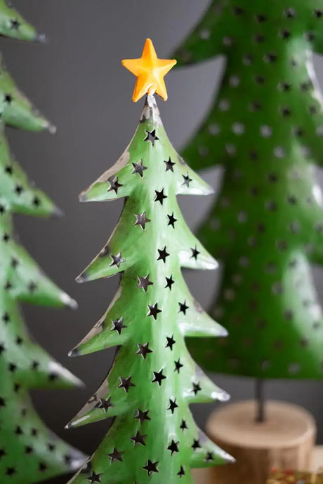 zoomed in on one of three green metal christmas trees with yellow star treetopper