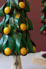 close up of green christmas tree with yellow fruit