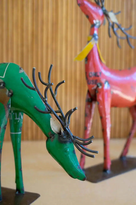 close up of green deer looking toward the ground with red deer in background