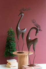 elegant dark metal deer on stands shown against red wall with mini christmas tree