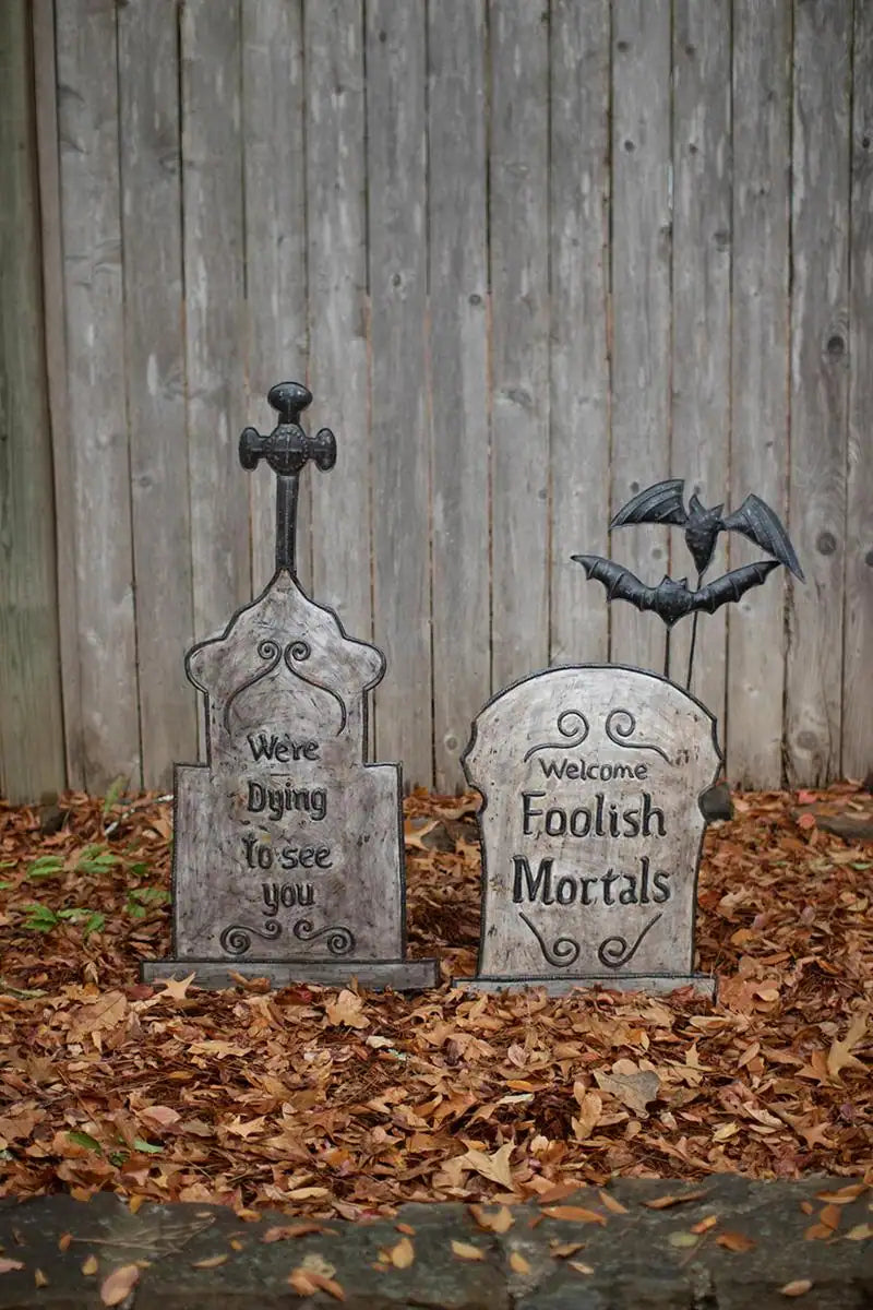 set of 2 hand hammered metal tombstones one with a cross atop the other with 2 bats - shown here in front of faded wood fence