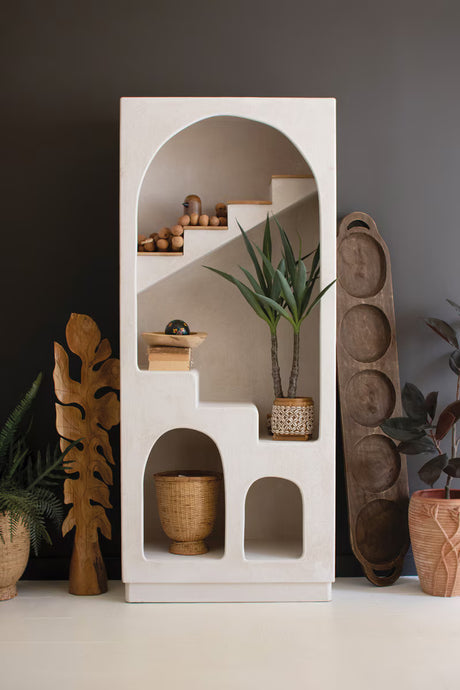 White shelving unit with arched design and stair details showing decorative items against a dark wall