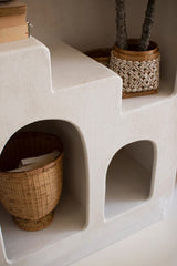 White plaster step details within shelving unit showing woven baskets and a plant to exemplify usage