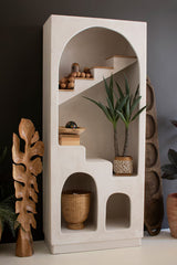 White plaster shelving unit with steps details and decorative items against a dark wall